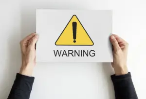 Elde tutulan, uyarı işareti ve warning yazısı içeren kağıt